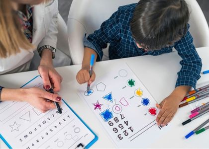 Criança concentrada durante sessão de avaliação neuropsicológica, apontando para fichas com formas geométricas e números coloridos sobre a mesa, ambiente clínico claro, fotografia realista